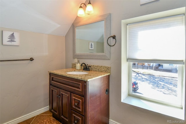 bathroom featuring vaulted ceiling, vanity, baseboards, and tile patterned floors