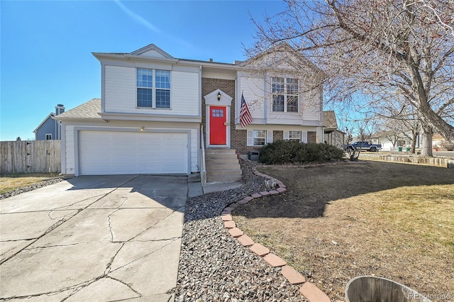 split foyer home featuring driveway, brick siding, an attached garage, fence, and a front yard