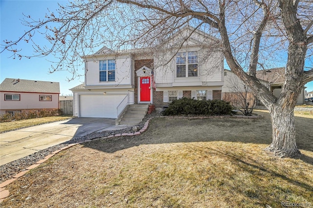 split foyer home with driveway, a front yard, a garage, and brick siding