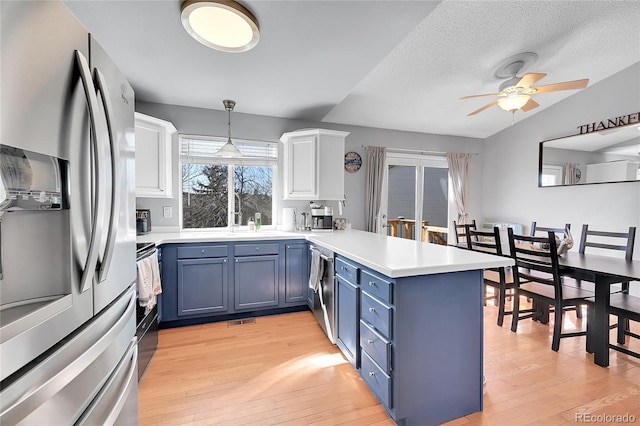 kitchen with light wood finished floors, stainless steel appliances, white cabinetry, blue cabinets, and a peninsula