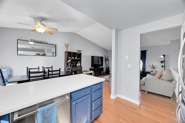 kitchen with light wood finished floors, open floor plan, blue cabinets, vaulted ceiling, and light countertops