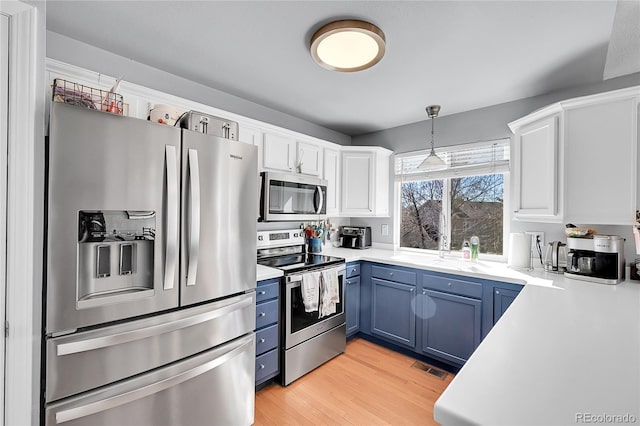 kitchen with blue cabinetry, stainless steel appliances, light countertops, white cabinetry, and light wood-type flooring