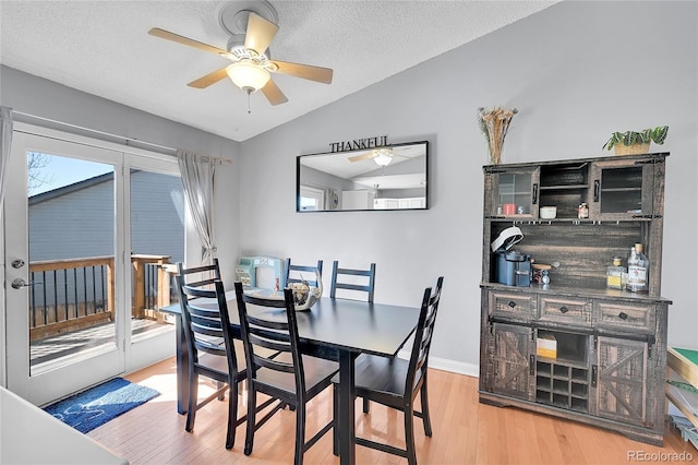 dining space featuring a textured ceiling, vaulted ceiling, and wood finished floors