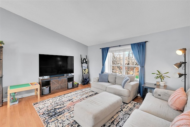 living area featuring vaulted ceiling, a textured ceiling, and wood finished floors