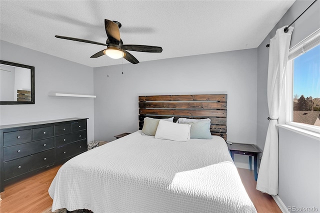 bedroom featuring ceiling fan, light wood-style flooring, and a textured ceiling