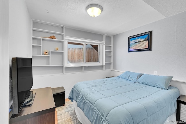 bedroom with a textured wall, a textured ceiling, and wood finished floors