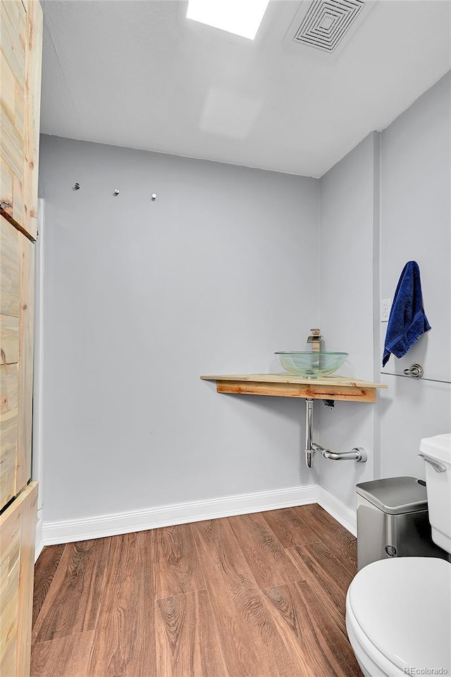 bathroom with visible vents, toilet, baseboards, and wood finished floors