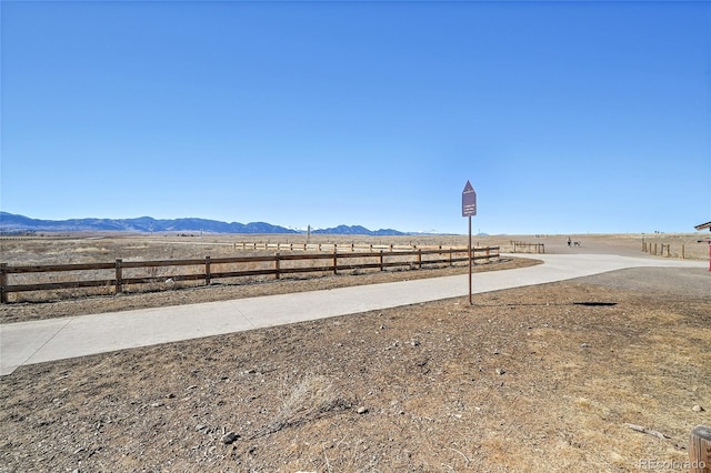 view of yard featuring fence, a mountain view, and a rural view