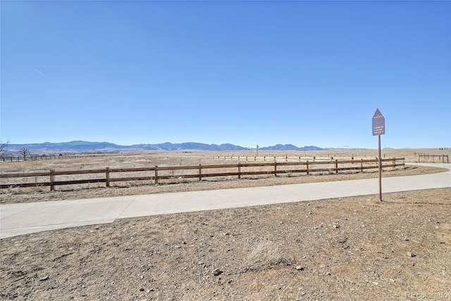 view of yard featuring fence, a mountain view, and a rural view