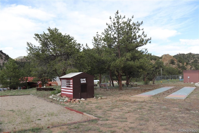 view of yard featuring a shed, a mountain view, and a playground