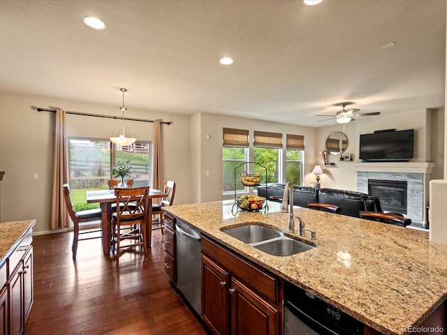 11945 S Saunter Ln, Parker, CO 80138 - kitchen with a glass covered fireplace, stainless steel dishwasher, dark wood-style floors, a ceiling fan, and pendant lighting