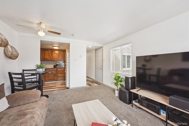 living area with light carpet, baseboards, and ceiling fan