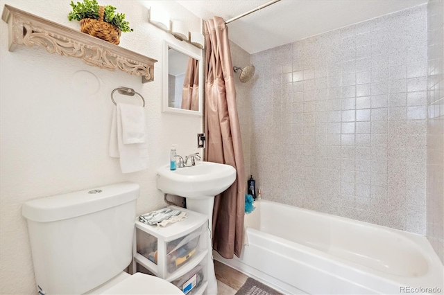 bathroom featuring toilet, shower / bath combo with shower curtain, and a textured wall
