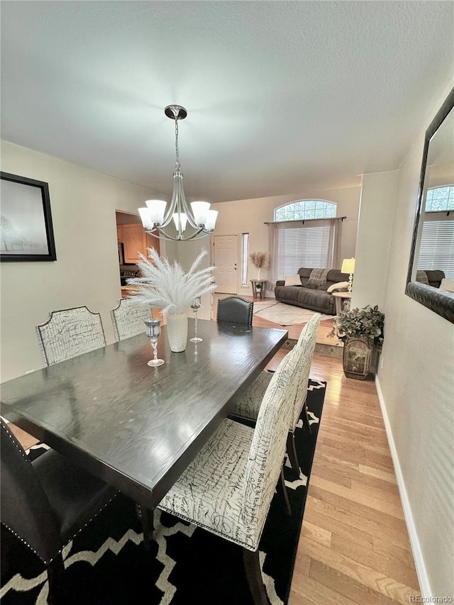 8769 S Dudley St, Littleton, CO 80128 - dining space with light wood-style floors, baseboards, and an inviting chandelier
