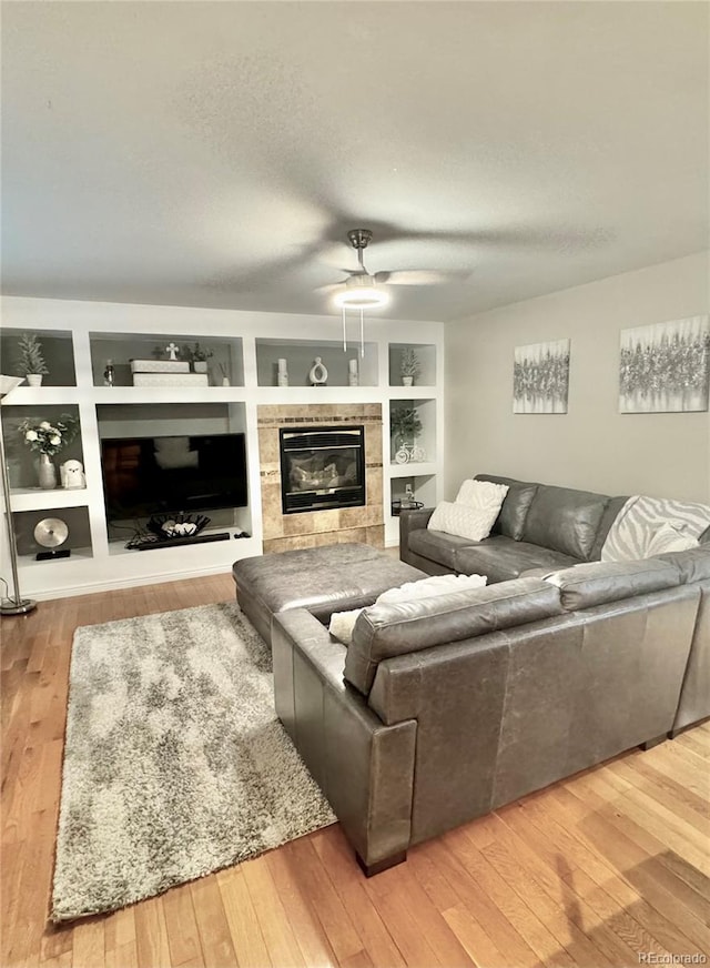 8769 S Dudley St, Littleton, CO 80128 - living room with ceiling fan, a fireplace, hardwood / wood-style flooring, and built in shelves