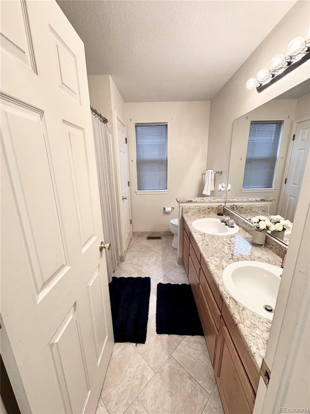 8769 S Dudley St, Littleton, CO 80128 - full bathroom with double vanity, toilet, a textured ceiling, and a sink