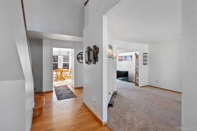 8441 Urban Ct, Arvada, CO 80005 - corridor featuring light wood-type flooring, light colored carpet, baseboards, and a chandelier