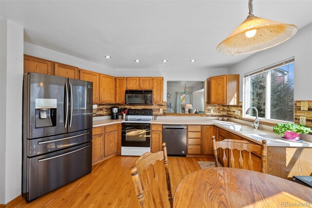 8441 Urban Ct, Arvada, CO 80005 - kitchen featuring light wood-style flooring, a sink, tasteful backsplash, stainless steel appliances, and light countertops