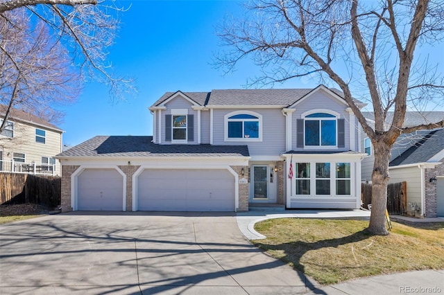 traditional-style house featuring a garage, brick siding, driveway, and fence