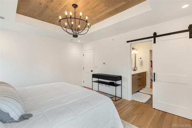 bedroom with wooden ceiling, a tray ceiling, light wood-style flooring, and a barn door