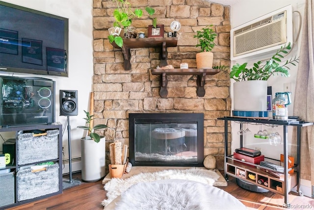 interior space with a wall unit AC, a stone fireplace, and wood-type flooring