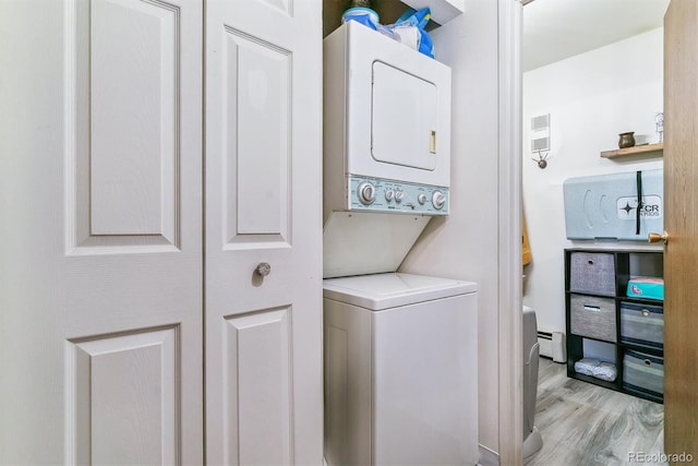 laundry room featuring stacked washer and dryer and light wood-type flooring