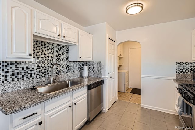 kitchen featuring light tile patterned floors, a sink, decorative backsplash, white cabinets, and appliances with stainless steel finishes