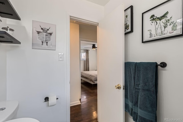 half bath featuring baseboards, toilet, and wood finished floors