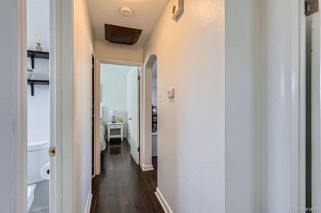 hall featuring arched walkways, baseboards, and dark wood-style flooring