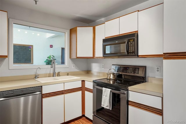 kitchen featuring appliances with stainless steel finishes, white cabinets, and sink