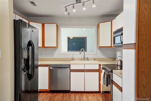 kitchen featuring light hardwood / wood-style flooring, white cabinetry, black appliances, and sink