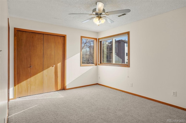 unfurnished bedroom featuring light colored carpet, ceiling fan, a closet, and a textured ceiling