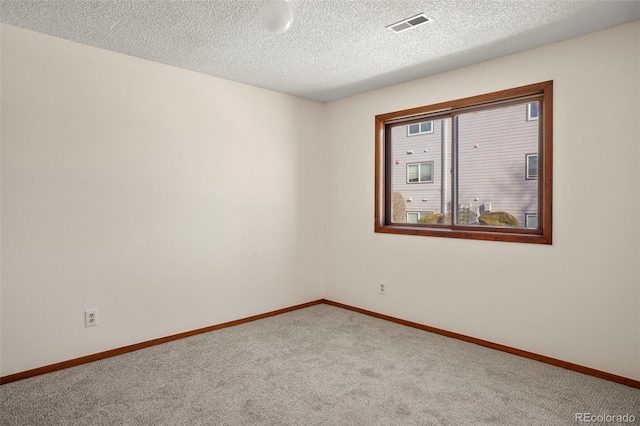 carpeted empty room with a textured ceiling