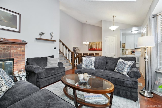 living room with a fireplace, high vaulted ceiling, a chandelier, and hardwood / wood-style floors