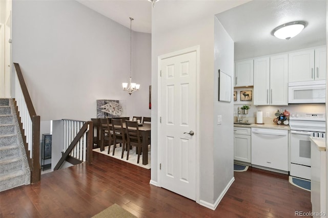 kitchen with white cabinetry, dark hardwood / wood-style floors, white appliances, and hanging light fixtures