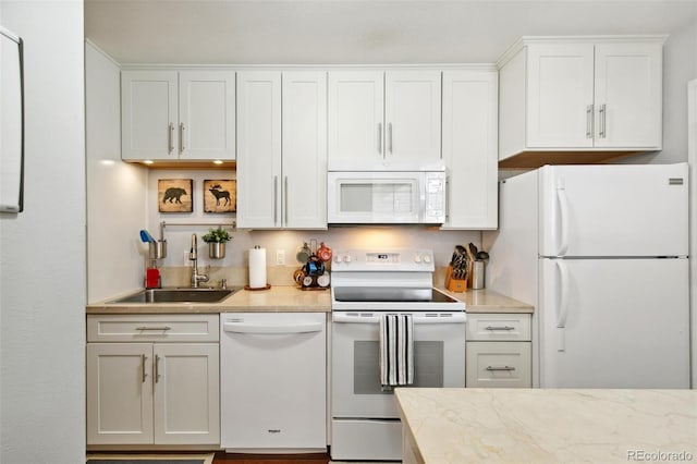 kitchen with white appliances, sink, and white cabinets