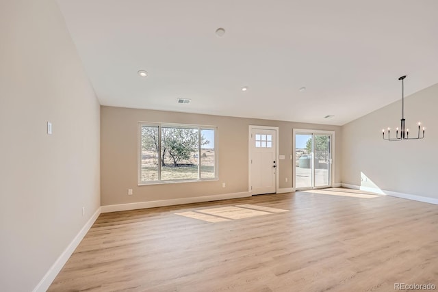 unfurnished room featuring lofted ceiling, light hardwood / wood-style floors, and a chandelier