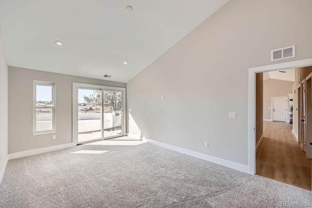 unfurnished room with light carpet and high vaulted ceiling