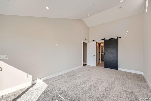 spare room featuring a barn door, lofted ceiling, and light carpet