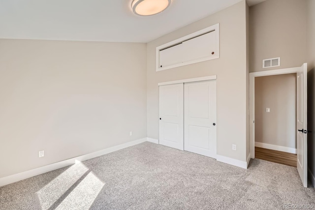 unfurnished bedroom featuring light carpet, vaulted ceiling, and a closet