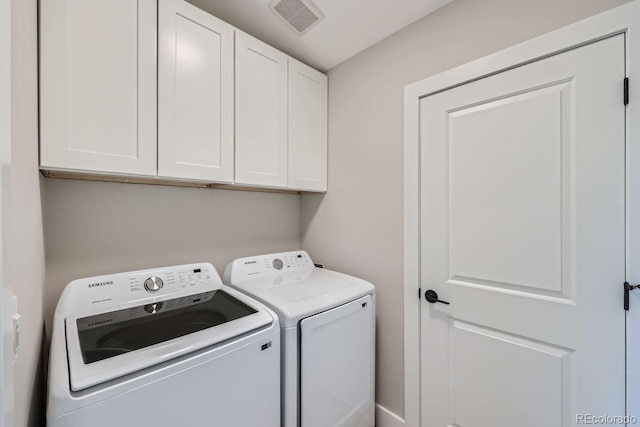 laundry area with washing machine and clothes dryer and cabinets