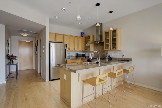 1438 Little Raven St Unit 306, Denver, CO 80202 - kitchen featuring stainless steel appliances, wall chimney range hood, a peninsula, baseboards, and a kitchen bar