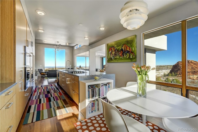 kitchen featuring sink, dark wood-type flooring, multiple ovens, stainless steel gas stovetop, and light brown cabinets