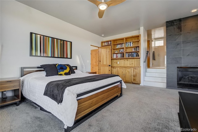 carpeted bedroom featuring ceiling fan and a tile fireplace