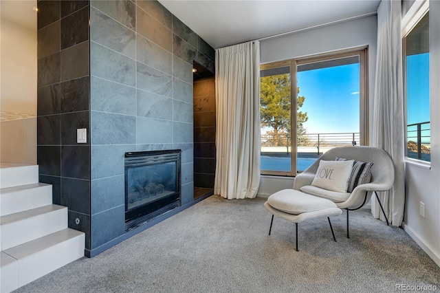 living area with a tiled fireplace, carpet, and tile walls