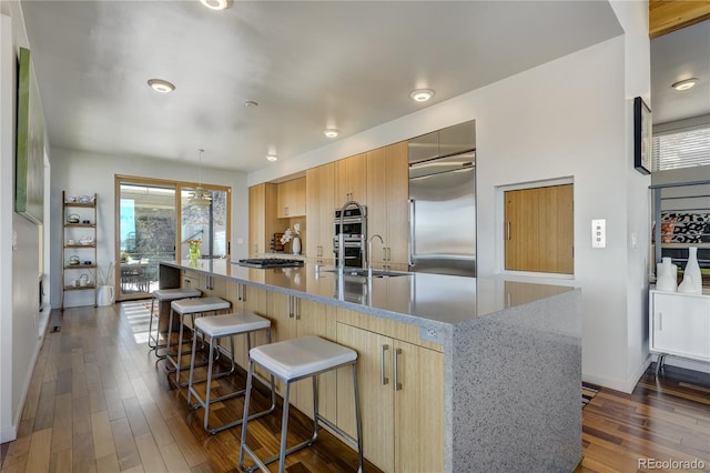 kitchen featuring light stone countertops, appliances with stainless steel finishes, dark hardwood / wood-style flooring, and a spacious island