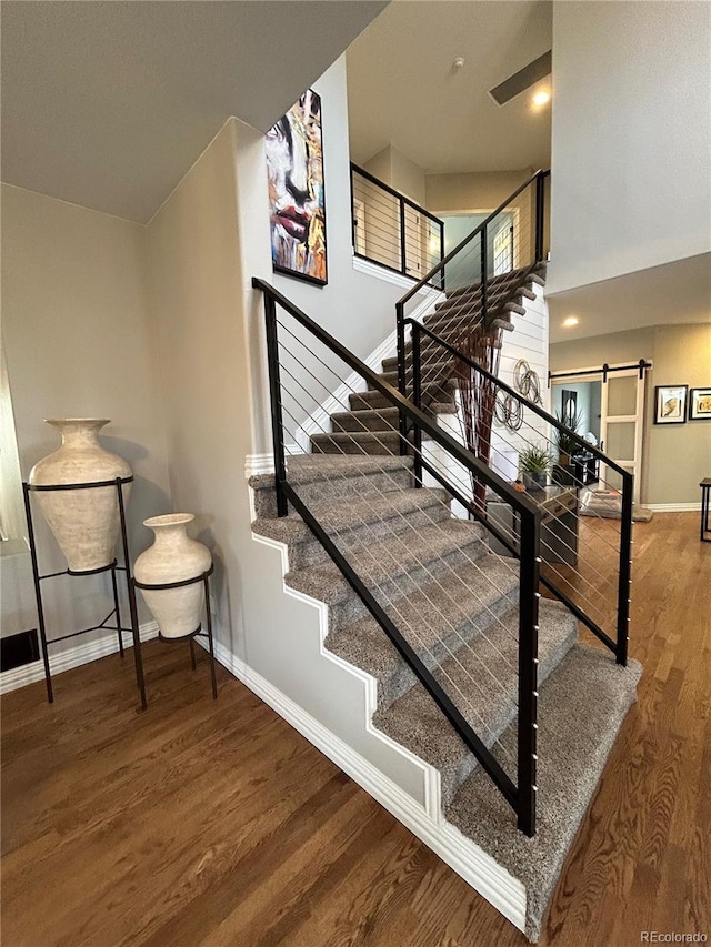 stairs with a barn door and wood-type flooring