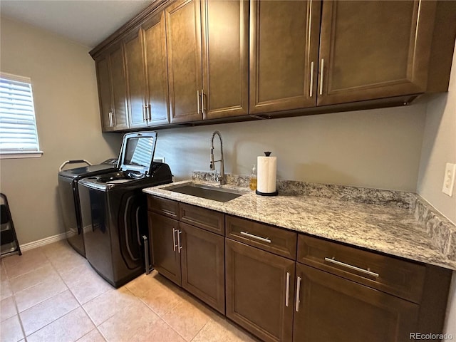 washroom with cabinets, light tile patterned floors, washing machine and dryer, and sink