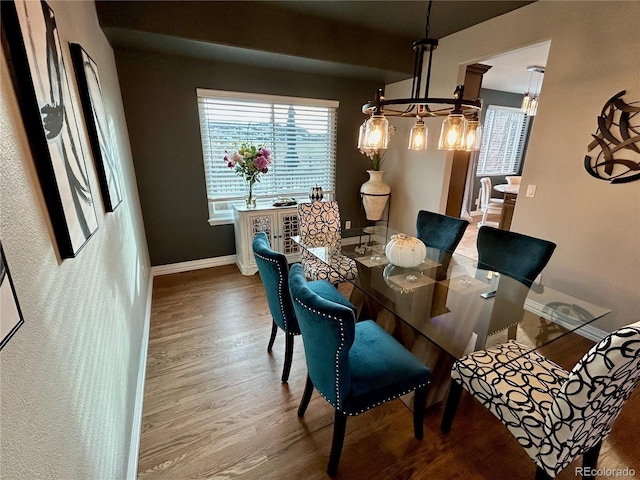 dining space featuring hardwood / wood-style flooring and an inviting chandelier