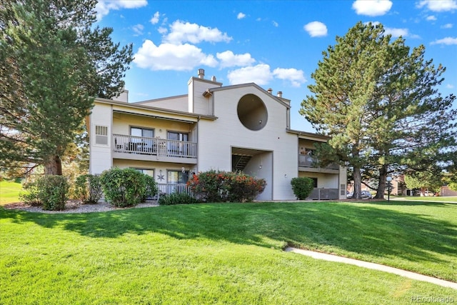 view of front of property featuring a balcony and a front lawn